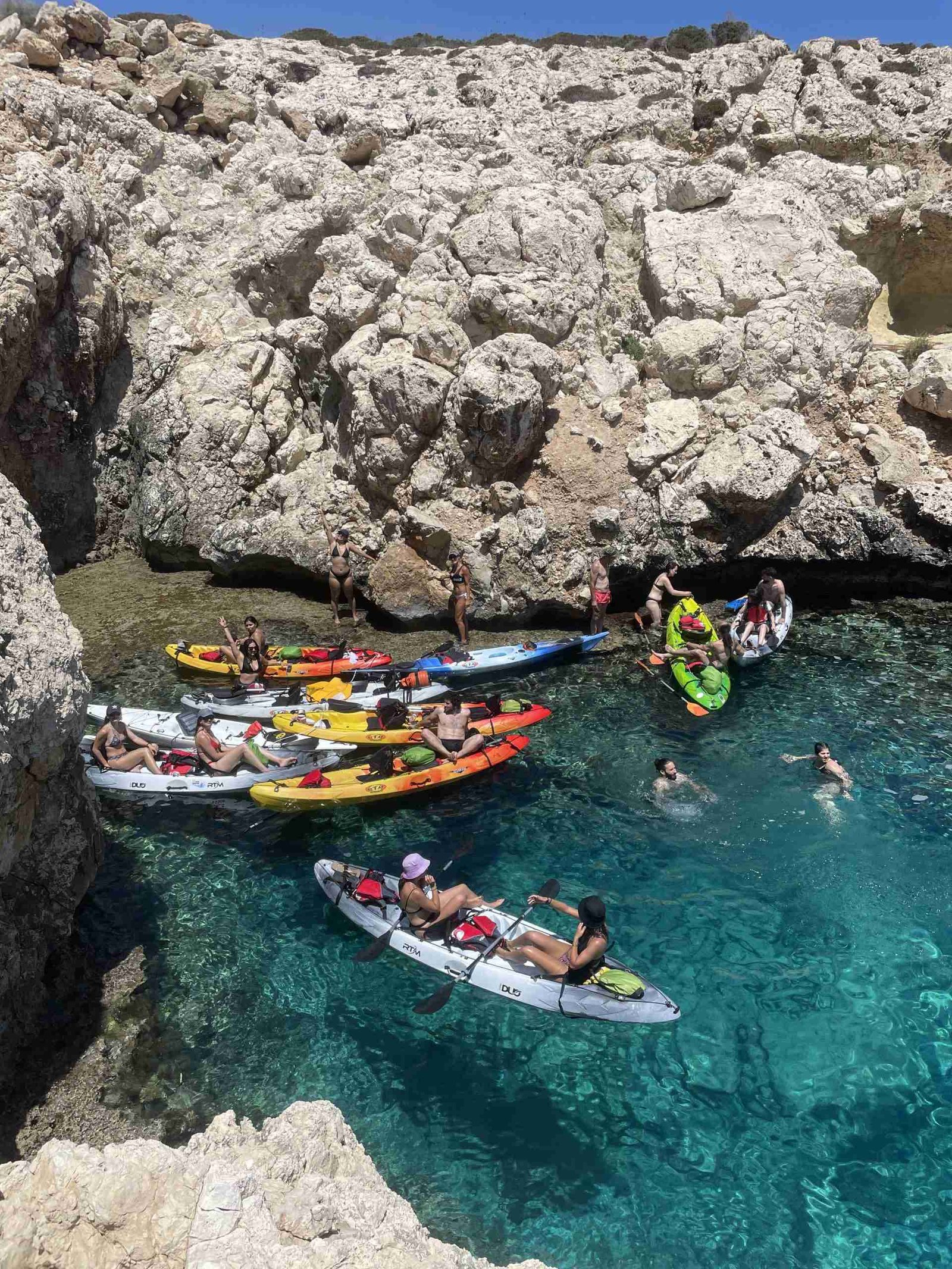 Cayaking vs canoeing - A group of people with their kayaks relaxing at blue coloured waters